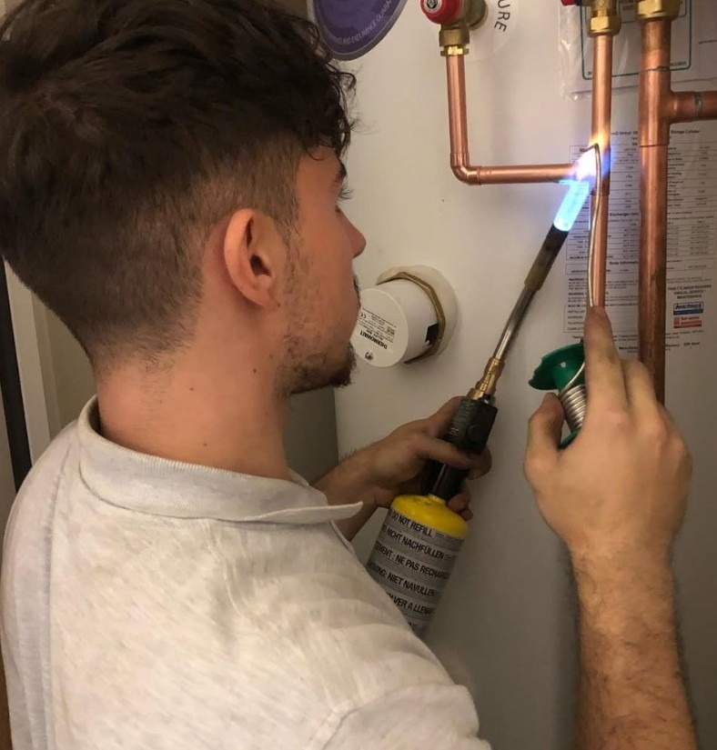 Plumber soldering copper pipework during a hot water and plumbing installation