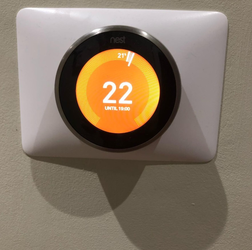 Nest smart heating thermostat mounted on a wall showing the room at 22 degrees