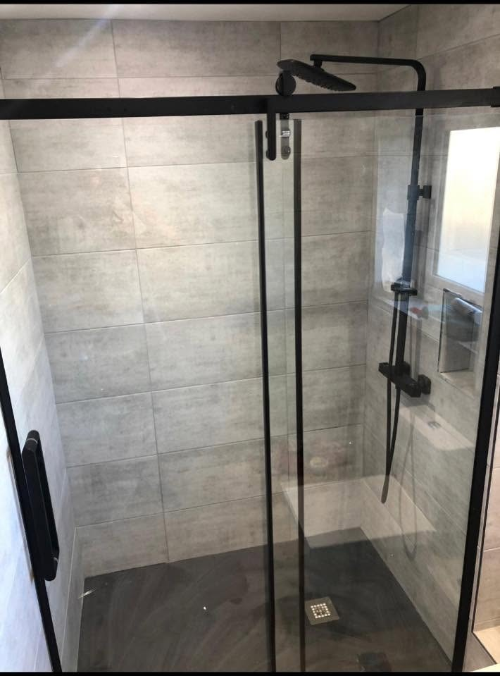 Walk-in shower with a matt black sliding door and large-format grey tiling
