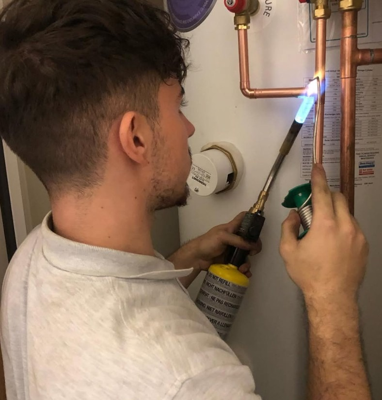 Reaction Plumbing & Heating engineer soldering copper pipework on a hot water cylinder
