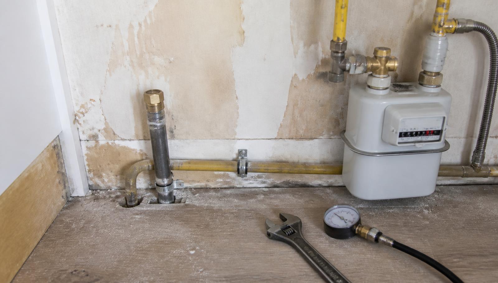 Capped-off domestic gas supply pipe beside a gas meter with a pressure test gauge